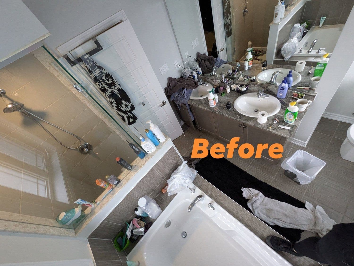 Cluttered bathroom with sink, mirror, and bath surfaces before cleaning